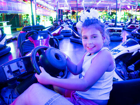 Smiling girl driving bumper car at amusement park funfair