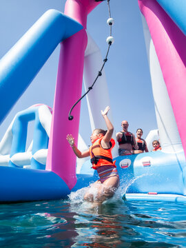 Girl jumping into the water from inflatable water park structure