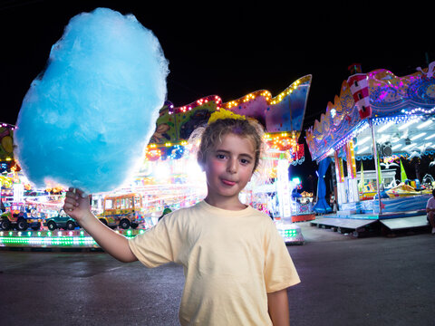 Boy showing her blue cotton candy at an amusement park at night