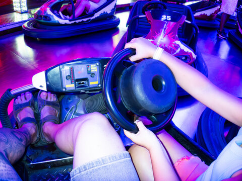 People driving bumper cars at amusement park enjoying funfair ride