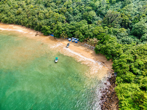 Aerial view of Jungle Beach featuring golden sand, turquoise waters, and lush tropical vegetation with small boats moored near the shore Unawatuna, Southern Province, Sri Lanka.