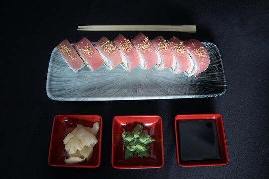 Avocado and Cucumber topped with Sesame Seeds on a Grey Ceramic Plate, Japanese Cuisine, Dark Mood Background . Fresh Tuna Sushi Roll with Cream Cheese,