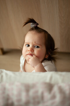 Baby Girl with Hand in Mouth Sitting on Floor at Home