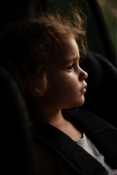 Thoughtful Little Girl Looking Out Car Window at Sunset