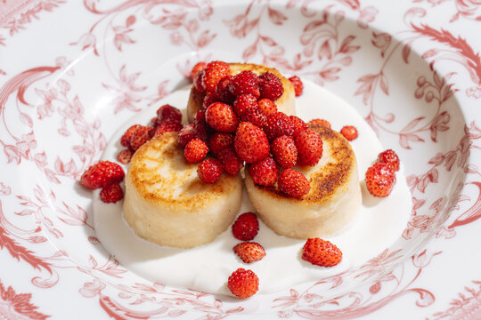 Cottage cheese pancakes topped with wild strawberries and sour cream
