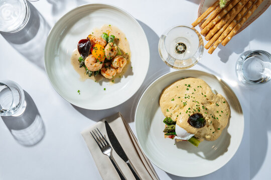 Shrimp and poached egg dishes served with sauce and asparagus