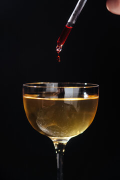 Red liquid drop falling into cocktail glass