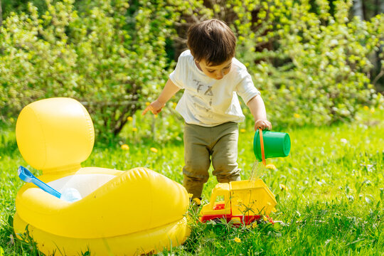 Child pouring water into toy truck in sunny garden