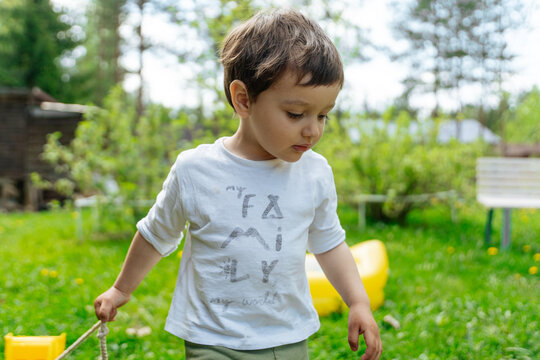 Child pulling toy truck in green backyard
