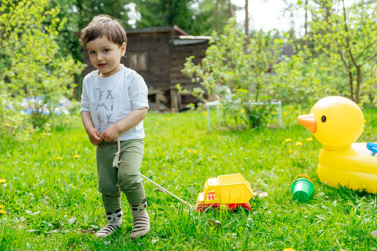Toddler pulling toy truck in backyard with inflatable duck tub