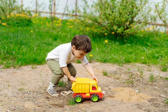 Child playing with toy dump truck in backyard