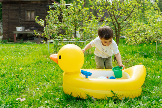 Child playing with water toys in inflatable duck tub outdoors