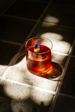Red cocktail with ice and flower garnish