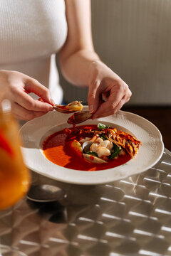 Person eating seafood soup with clams and prawn