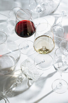 Title:Red and white wine in glasses surrounded by empty stemwar