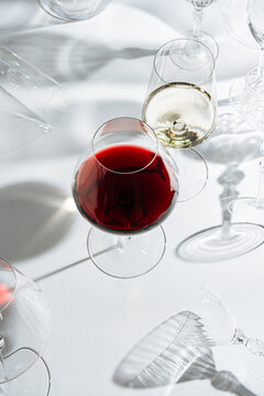 Title:Red and white wine glasses surrounded by empty glassware 