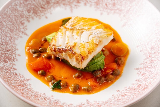 Seared white fish with vegetables and capers in tomato sauce