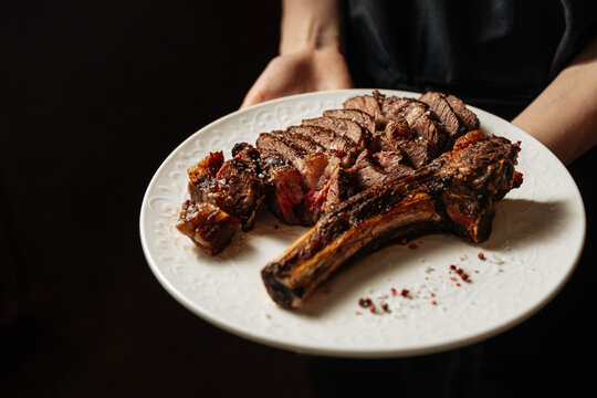 Sliced tomahawk steak served on white plate