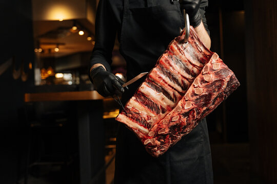 Butcher cutting raw beef ribs