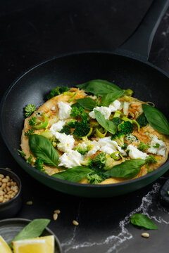 Vegetable omelette with fresh herbs and cheese in pan