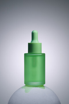 A close-up shot of a green dropper bottle with spilled liquid