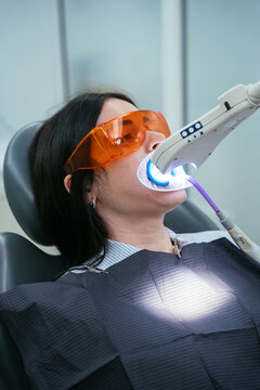 Woman receiving dental teeth whitening treatment with uv light