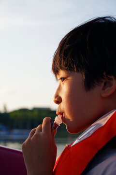 Closeup of a Chinese boy sucking on a sweet treat

