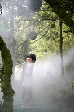 Chinese boy in a forest with mist spraying water