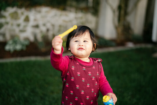 happy little girl  blowing bubbles in their yard. 