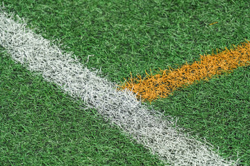 Obraz premium Green synthetic grass, artificial turf sports field with yellow and white lines.