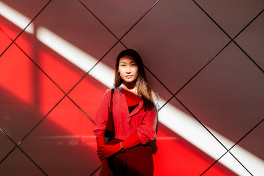 Woman in stands against geometric wall with light.