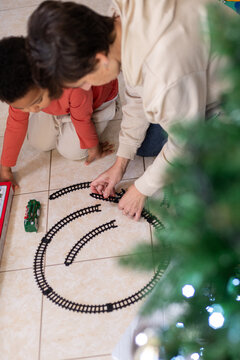Child and Adult Build Train Track on Floor Near Christmas Tree