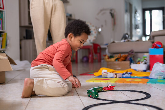 Smiling Child Plays With Toy Train on the Floor in a Living Room