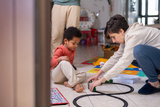 Child and Mother Play Together With Train Set on the Floor