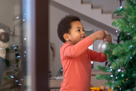 Child Decorates Christmas Tree in Living Room During Holiday Season