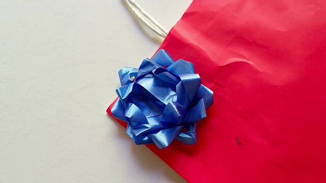 Red gift bag with blue ribbon bow isolated on white background