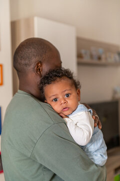 Father holding his baby boy who is looking at the camera