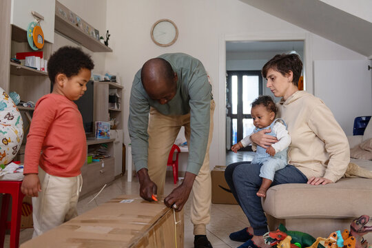 Father unboxing a large package with his family at home