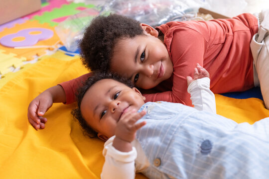 Two Smiling Children Play Together on a Colorful Mat 