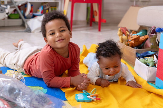 Two Children Play Together on a Colorful Mat in a Living Room