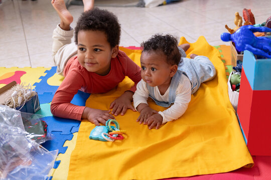 Siblings Play on Colorful Mat in Room With Toys During Daytime