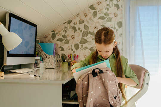 Packing Backpack at Home Study Desk Before Leaving for Day