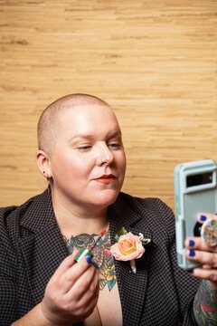 Woman With Shaved Head Using Phone Mirror