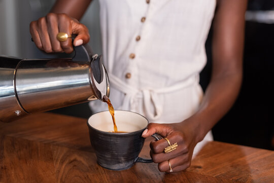 Pouring Coffee Into a Cup at a Kitchen Counter in the Morning
