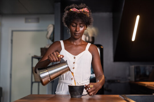 Black woman pouring coffee in cup 