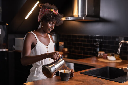 Woman poring coffee in cup from moka pot 