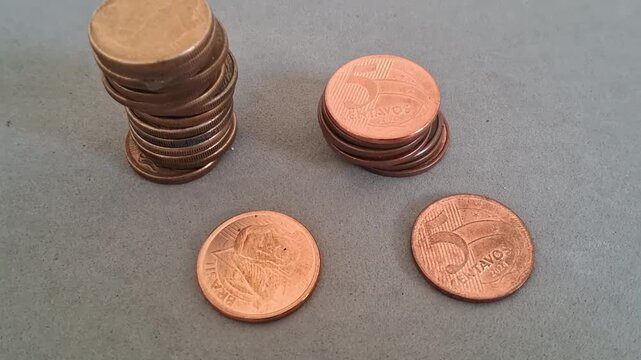 Stacked and loose brazilian coins captured in this high resolution professional macro studio motion video footage