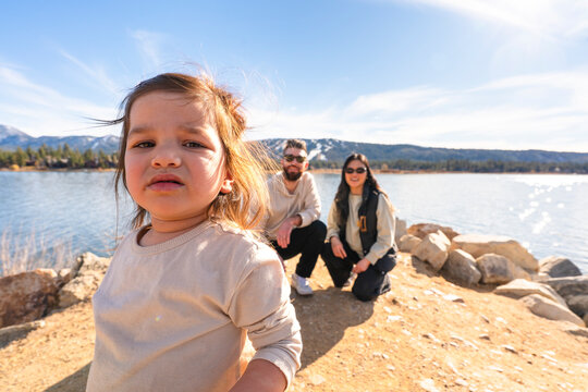 Family Enjoys Time by the Lake With Child Playing on the Shore