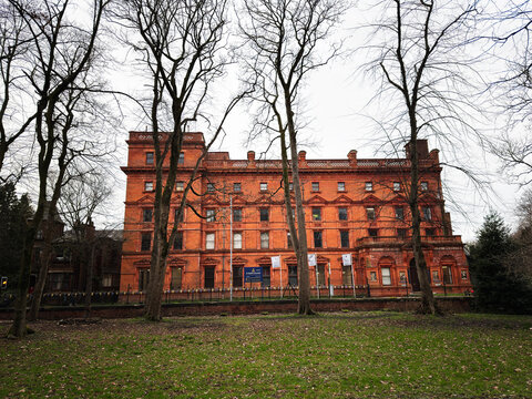 Red brick historic St Bede's College Catholic HMC Independent School building in Alexandra Park, Manchester, UK framed by bare winter trees