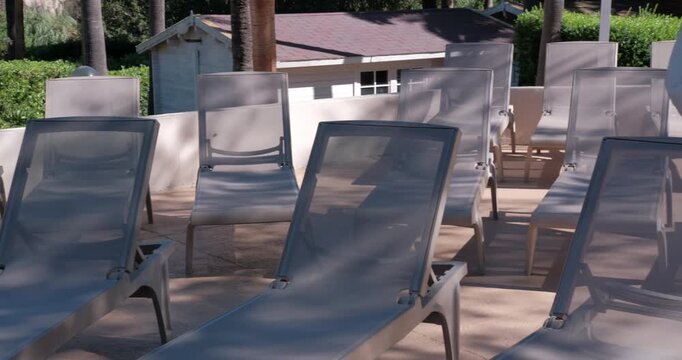 PORTOCOLOM, MALLORCA, SPAIN - OCTOBER, 2025: Rows of empty sun loungers under intense midday sun creating strong shadows and contrast, resort vibe